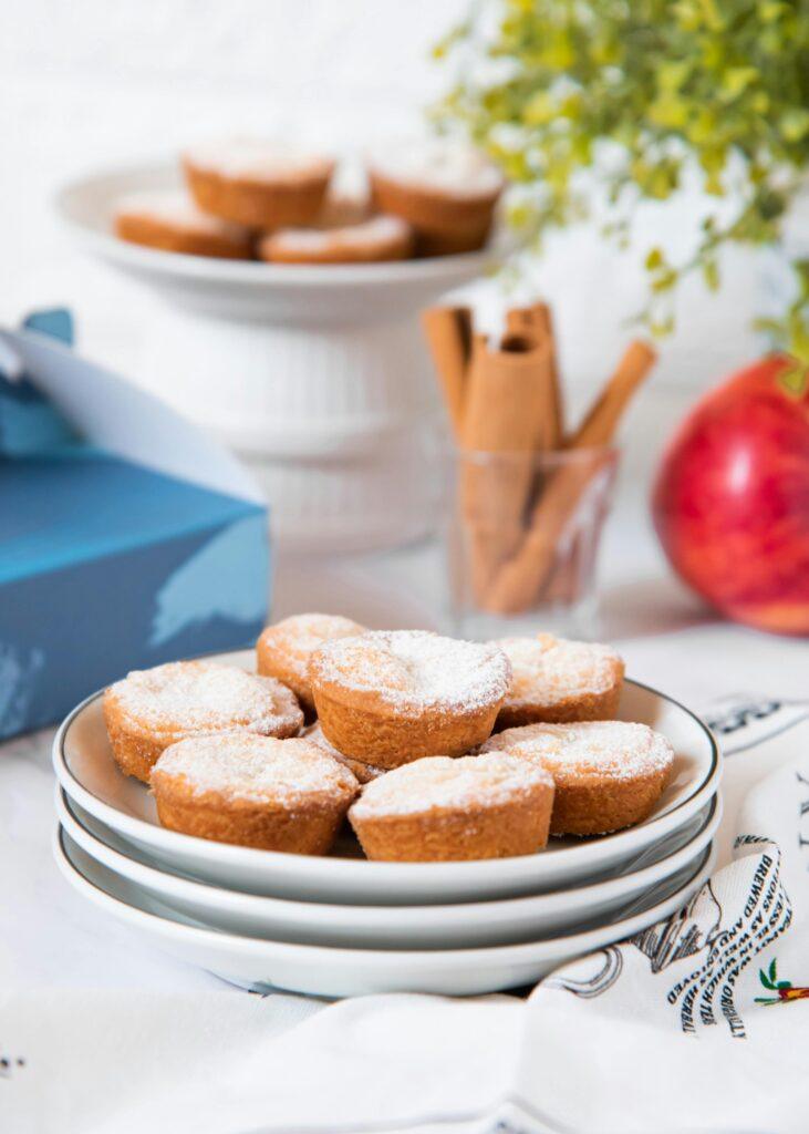 A stack of healthy apple oatmeal muffins dusted with powdered sugar on plates.