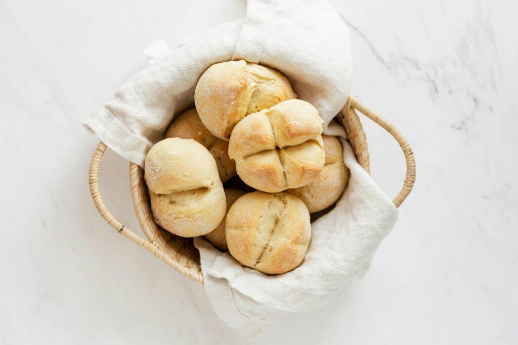 Top view of fresh homemade bread rolls in a wicker basket on a marble surface.