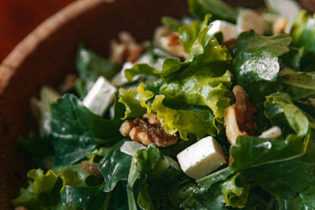 Close-up of a vibrant green salad with walnuts and cheese for a healthy meal.