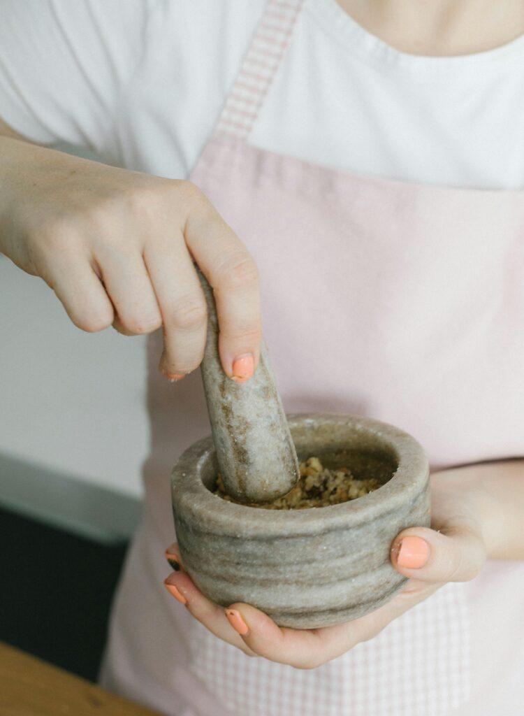 Hands using a mortar and pestle to grind ingredients, showcasing culinary preparation.
