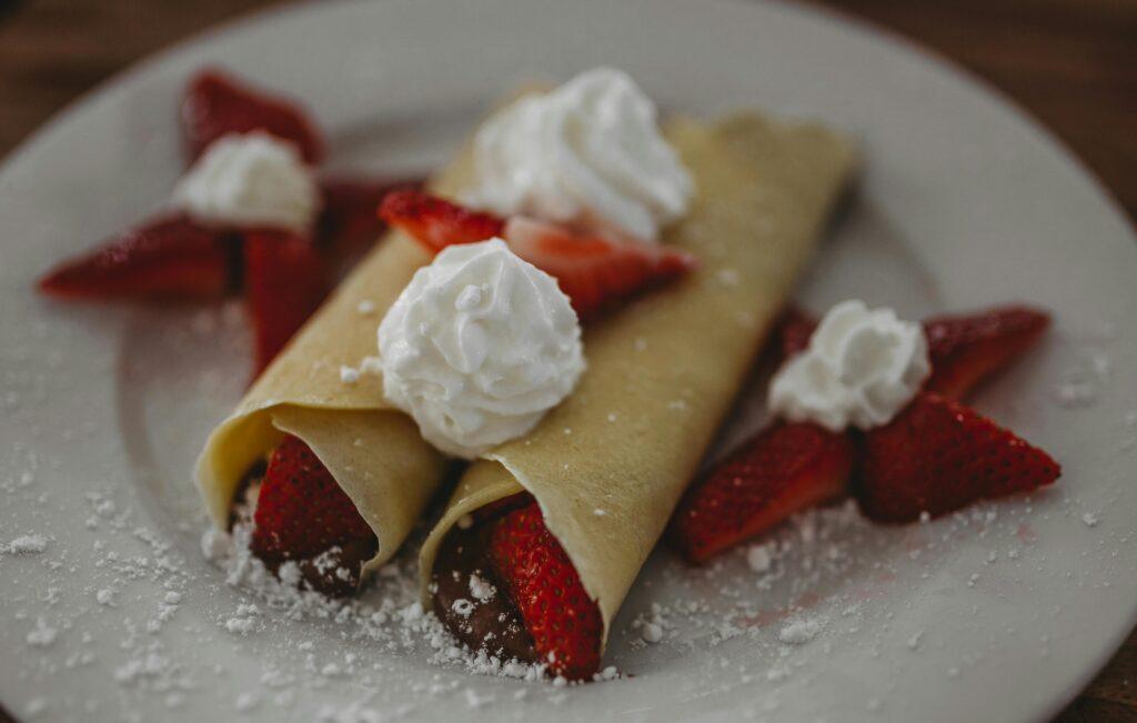 Freshly made strawberry buttermilk crepes topped with whipped cream, perfect for a delightful breakfast or dessert.