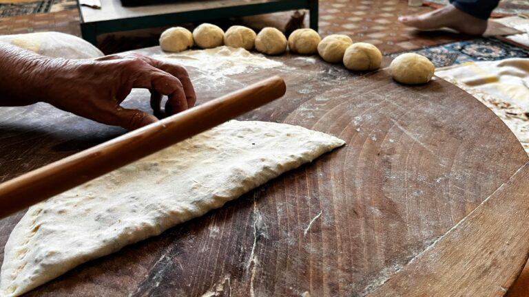 Close-up of homemade bread kneading with dough balls and a rolling pin.